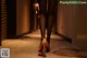 A woman in black stockings and high heels walking down a hallway.