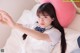 A young woman laying on a bed with a pink pillow.