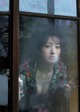 A woman looking out of a window with a broken glass.