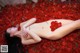 A naked woman laying on a bed of red rose petals.