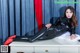 A woman in a black latex outfit laying on a white table.