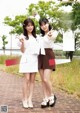 Two young women standing next to each other on a brick walkway.