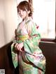 A woman in a green and pink kimono leaning against a window.