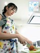 A woman in an apron cutting a tomato with a knife.