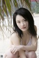 A woman in a white bikini sitting on the beach.