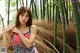 A woman in a pink and black dress posing in front of a bamboo forest.