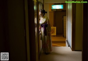 A woman in a kimono standing in a hallway.