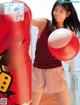 A woman holding a red and white ball in front of a punching bag.