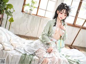 A woman in a green kimono sitting on a bed.